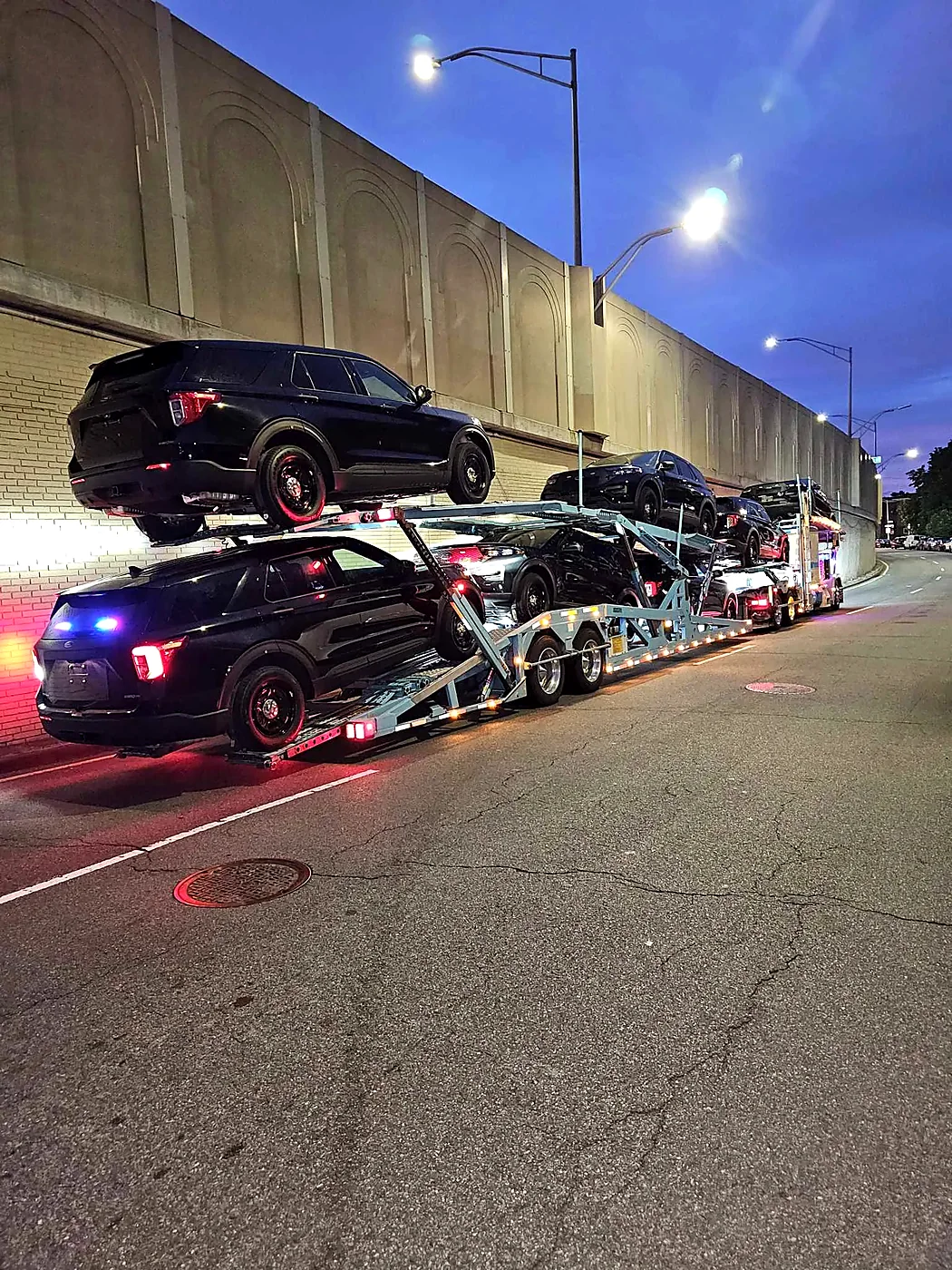 Loaded multi-car carrier parked at night.